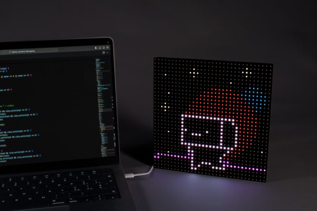 Mircolino sulla matrice LED accanto al laptop con editor di codice